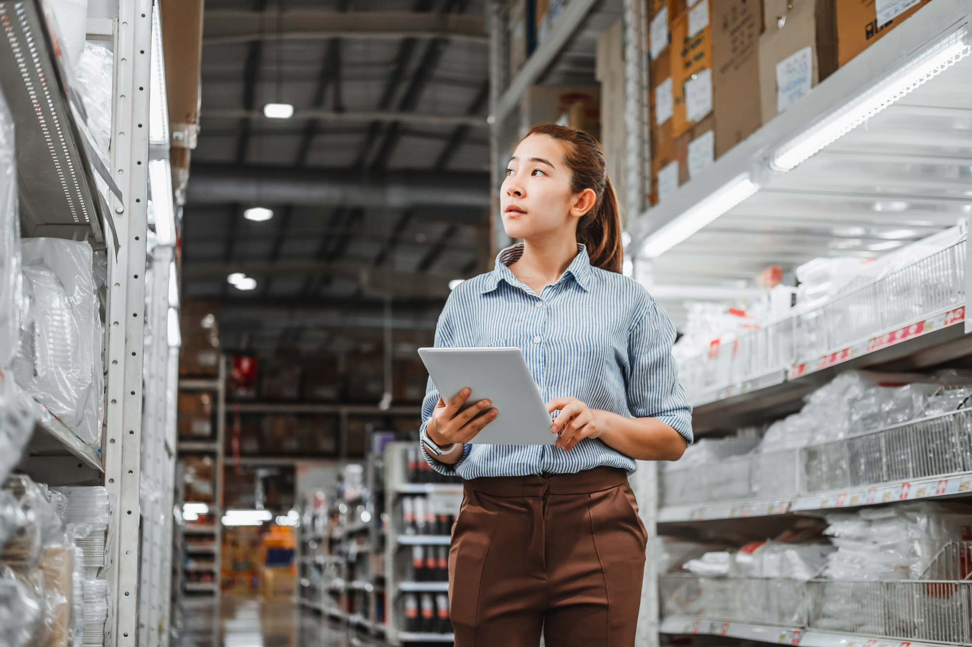 woman with an mba in logistics and supply chain management looking at items in a warehouse