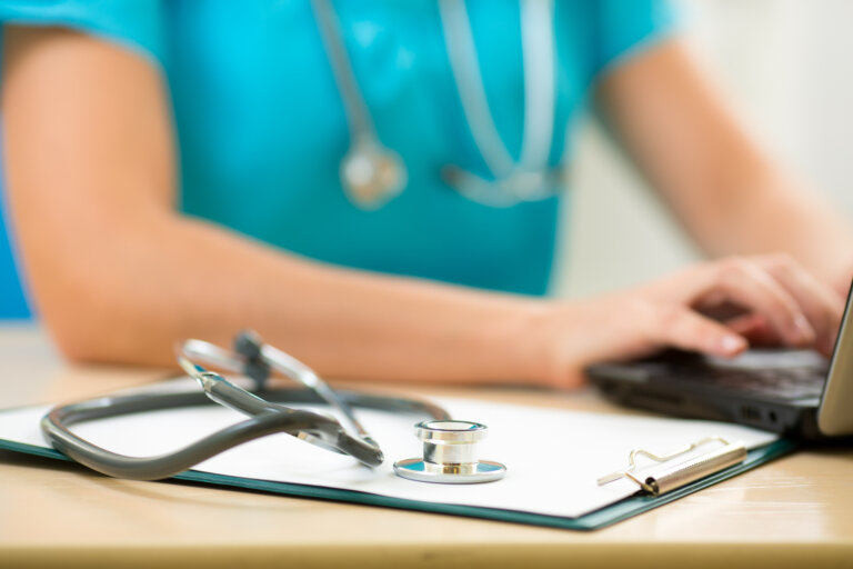 close-up of stethoscope on clipboard with professional health studies student typing in the background