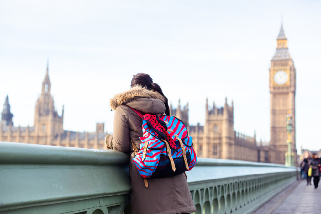 Person with colourful backpack looking over the River Thames with Big Ben and the House of Parliament in the background