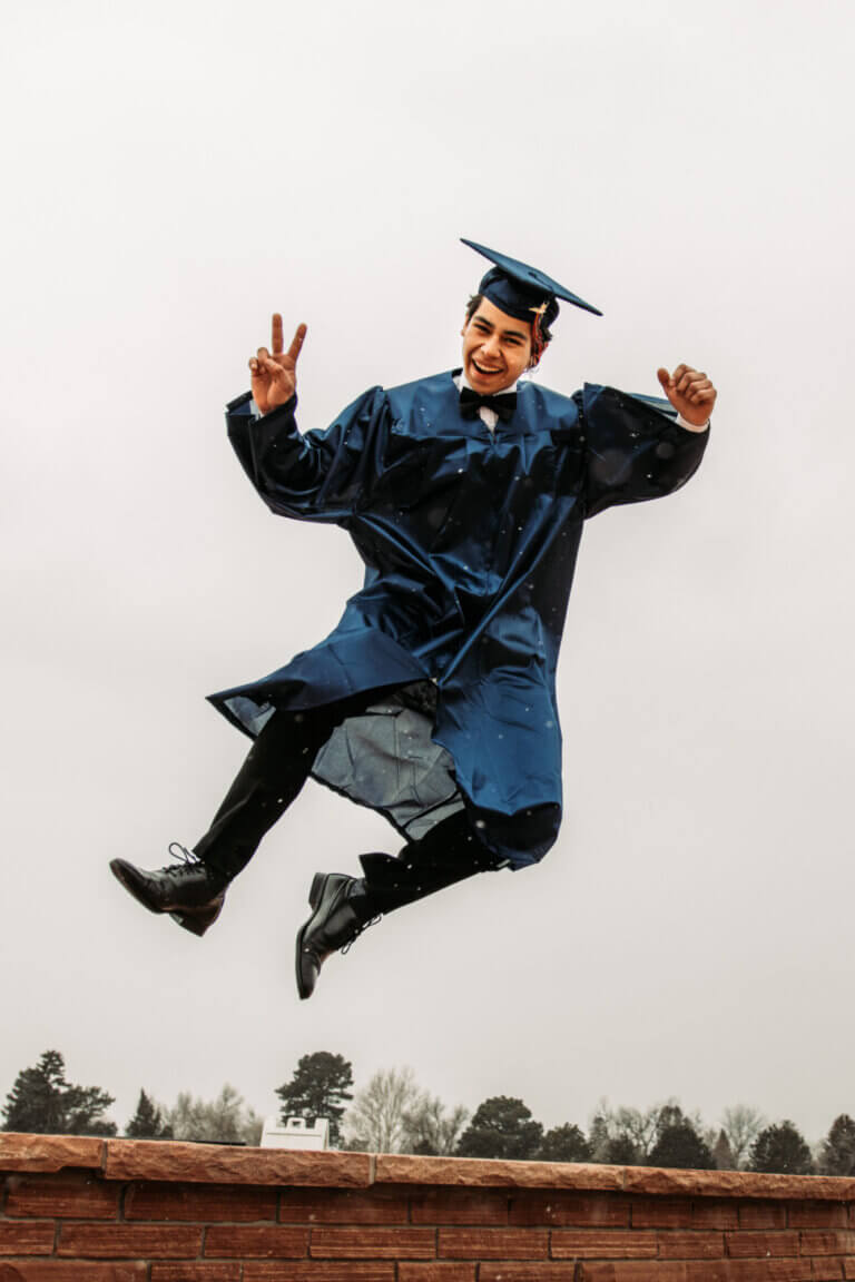 A student in his graduation gown jumping in the air