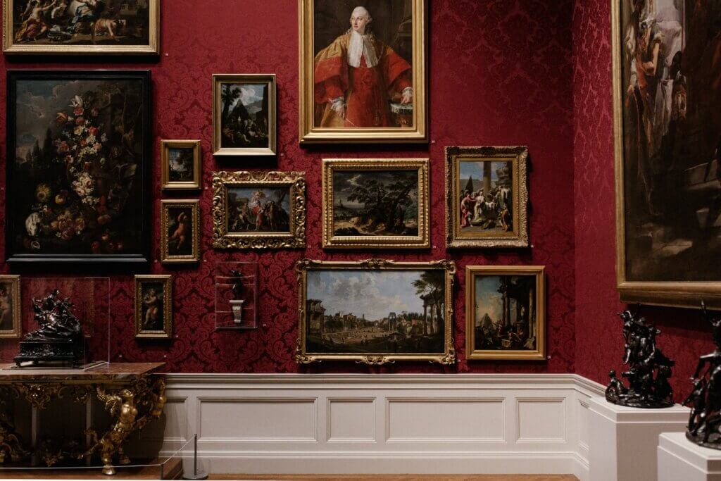 Oil paintings from a historical era placed on top of a red wall