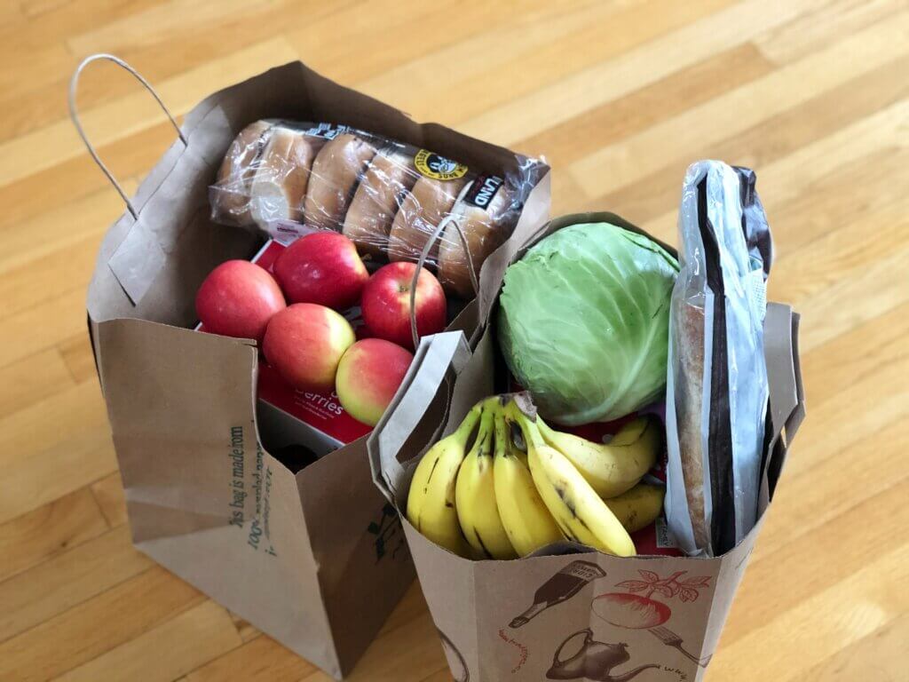 Two shopping bags on the floor with fruits and vegetables