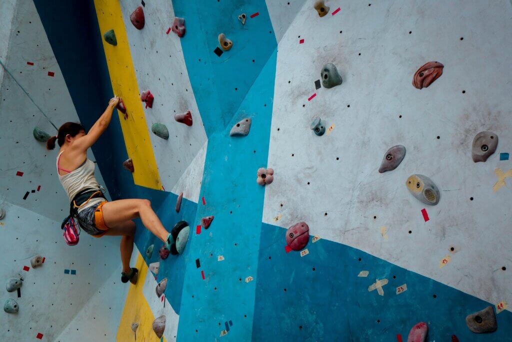person rock climbing on a blue wall