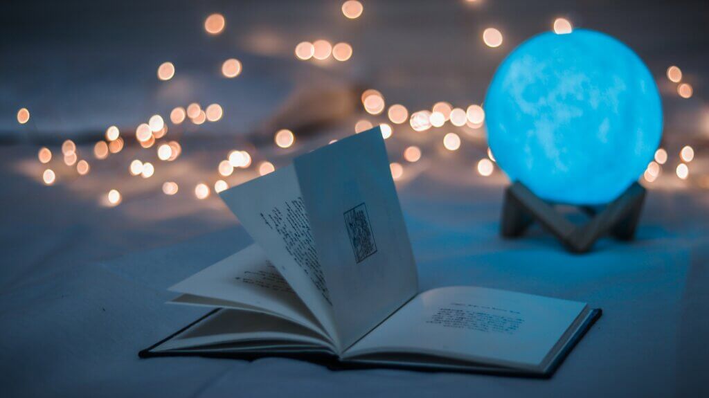 An open book on the floor with some lights on in the background