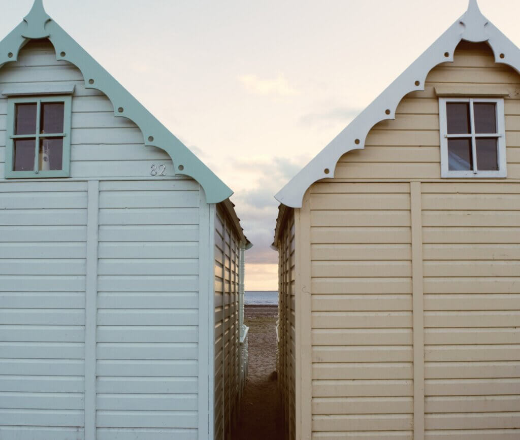 A couple of colourful wooden cabins on Mersea Island beach
