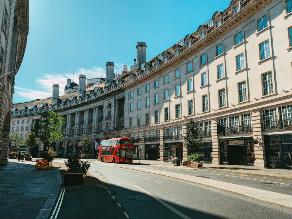 A red London bus driving on Regent Street in central London