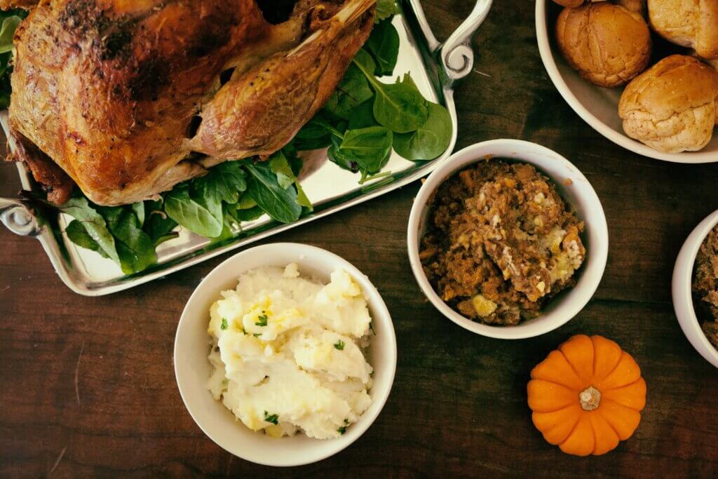 A roast dinner with a roasted chicken, mash, stuffing, bread and pumpkin