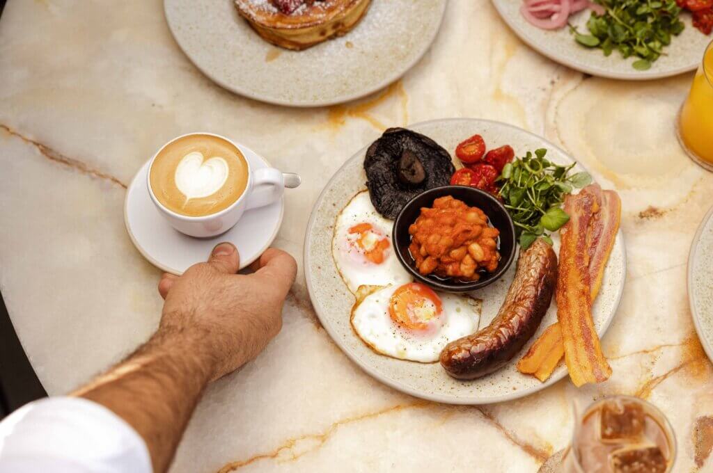 English breakfast at a restaurant being served with a coffee with milk art