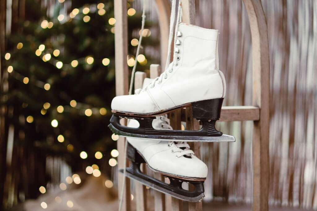 ice skates hanging up with a Christmas tree with lights on in the background