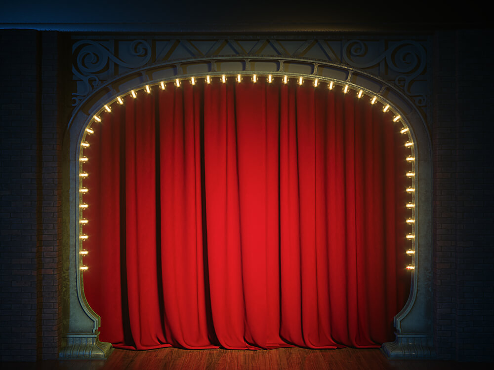 A red theatre curtain with lights around the edge