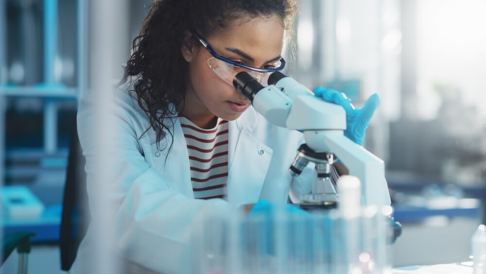 A female scientist looking at liquid through a microscope
